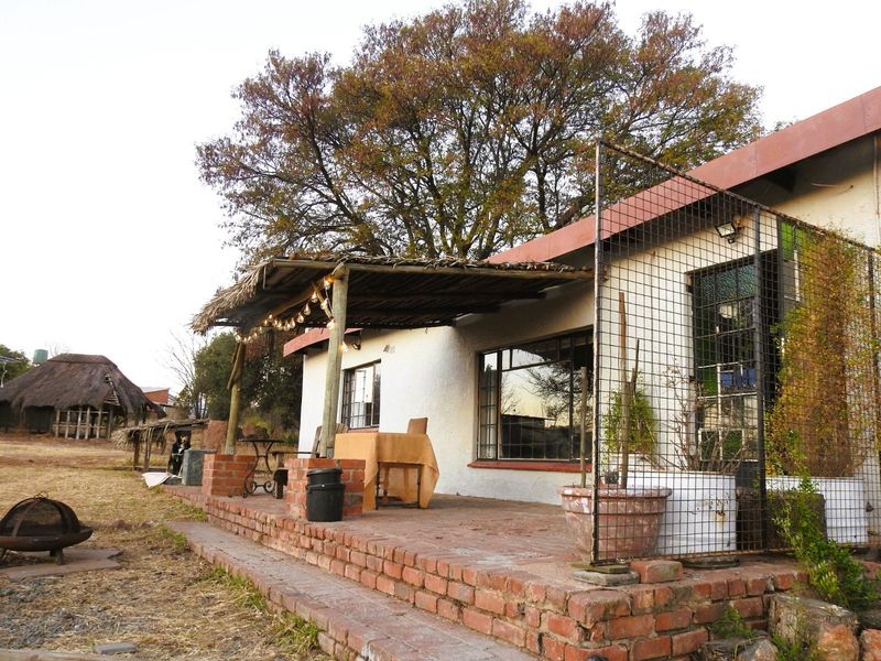 A rustic outdoor patio area featuring a brick base and a thatched roof covering, providing a covered space for outdoor relaxation.