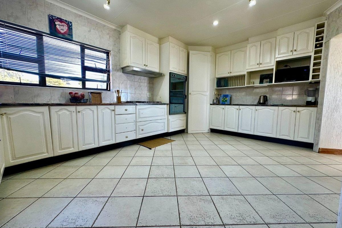 A functional kitchen featuring white built-in cabinetry, tiled flooring, a built-in oven, and an extractor fan, offering a clean and practical workspace.