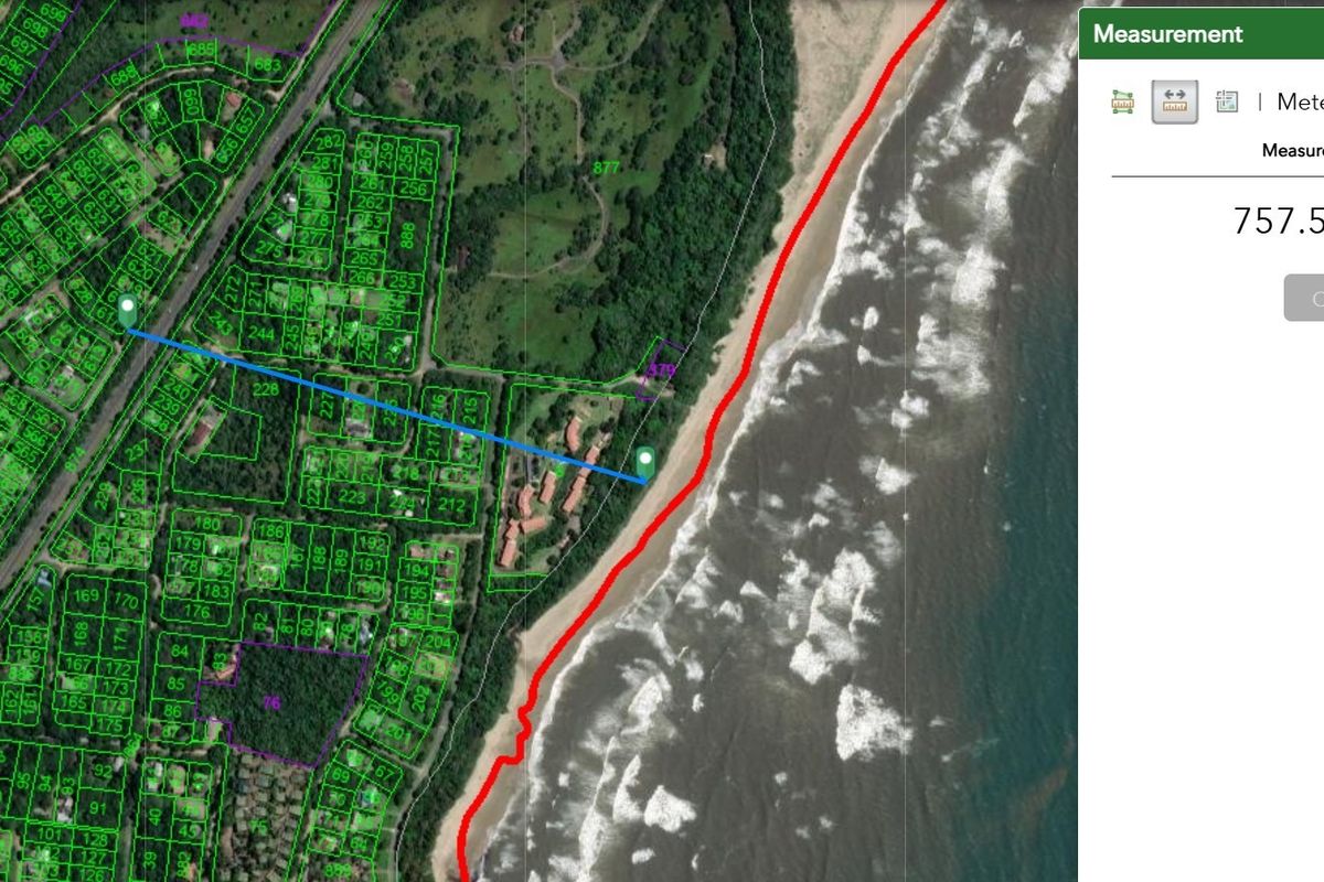 Aerial satellite view showing residential land plots in proximity to the coastline.