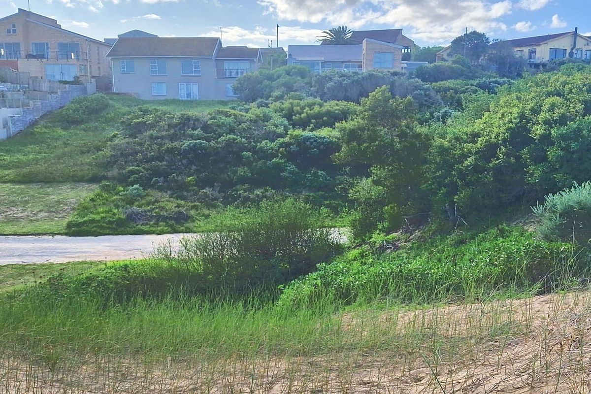 A view of the rear of the residential property, showcasing the natural coastal landscape, sand dunes, and surrounding vegetation.
