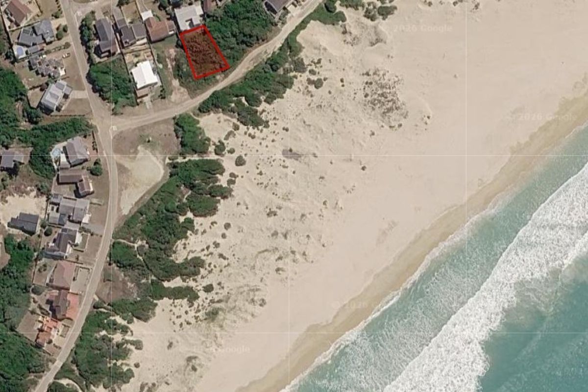 Aerial view of a vacant residential plot situated in a prime coastal location with direct proximity to the beach.