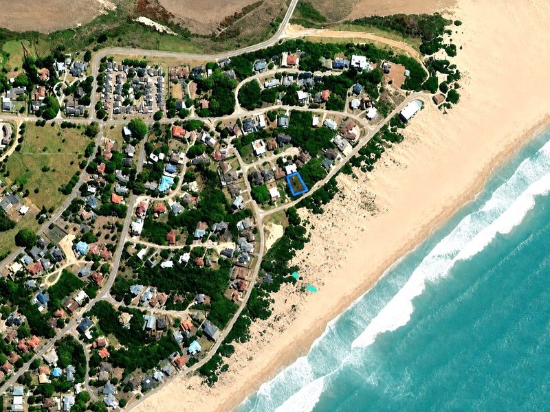 An aerial view showing the residential plot highlighted in blue, situated in a prime coastal location near the beach.