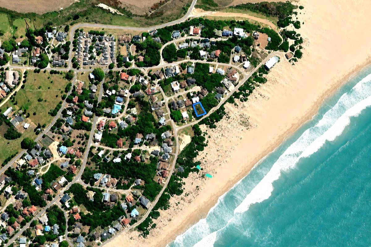 An aerial view showing the residential plot highlighted in blue, situated in a prime coastal location near the beach.