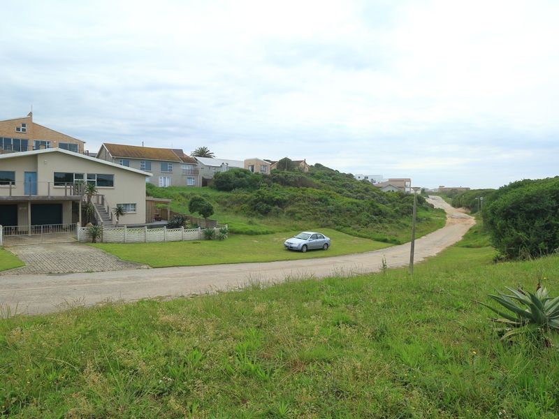 A view of the unpaved street and surrounding residential landscape, showcasing the natural terrain and access to the property.