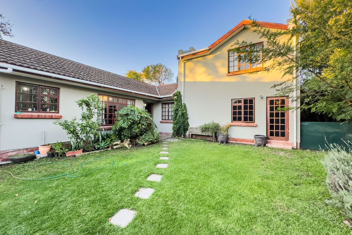 Rear view of the house featuring a well-maintained lawn, stone garden path, and traditional timber-framed windows and doors.