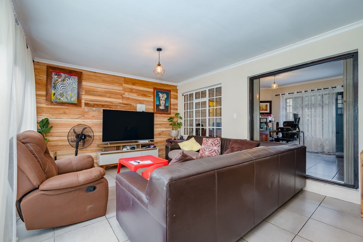 A living room featuring timber wall cladding, tiled flooring, and a sliding glass door leading to an adjacent space.