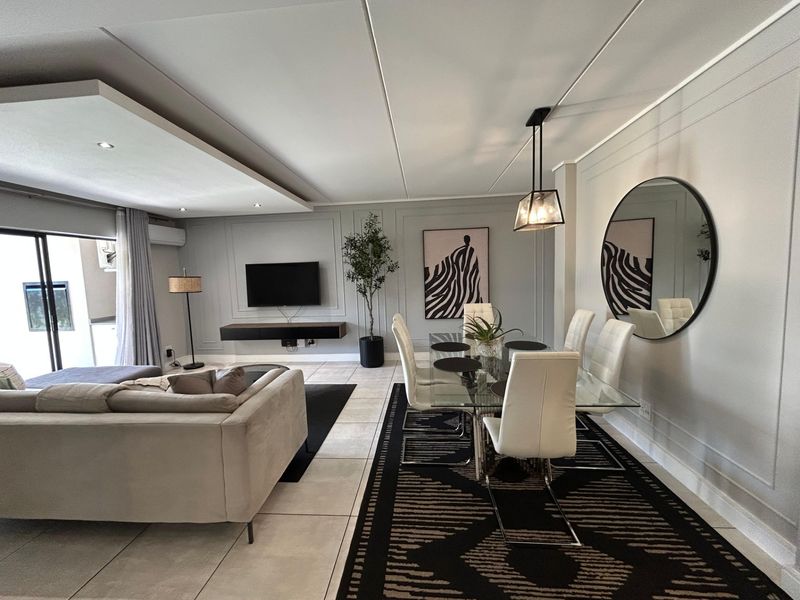 Spacious open-plan living and dining area featuring elegant wall paneling, recessed ceiling details, and large sliding doors leading to an outdoor space.