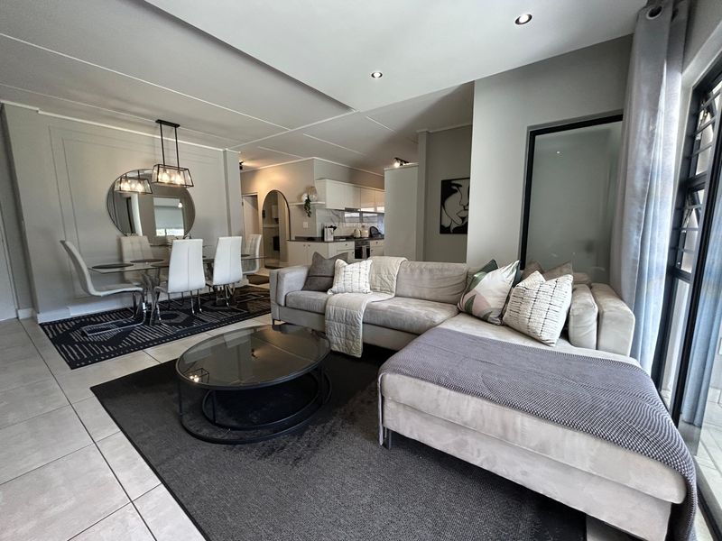 Spacious open-plan living and dining area featuring modern tiled floors, recessed lighting, and a well-appointed kitchen with built-in cabinetry and appliances.