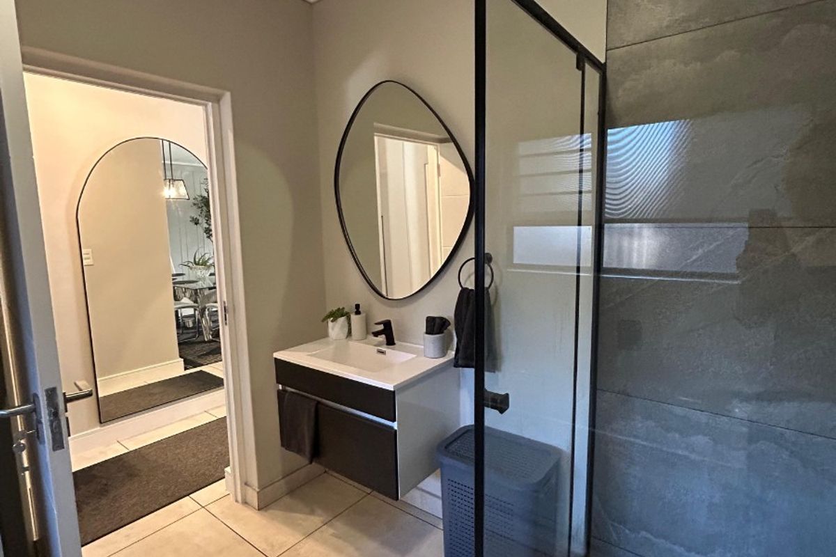 Modern bathroom featuring a floating vanity, black tapware, and a spacious walk-in shower with large format grey tiling.