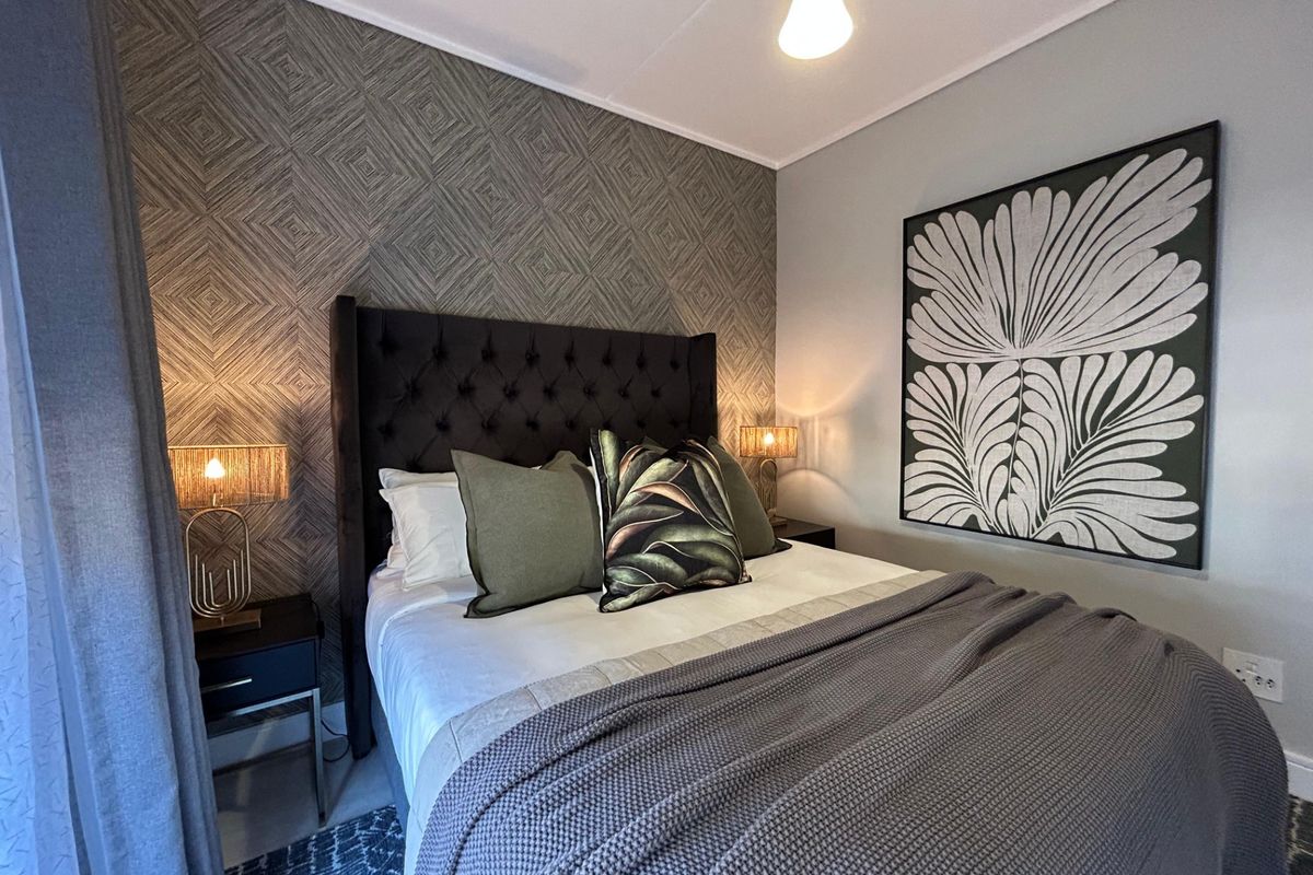 A well-presented bedroom featuring a decorative textured accent wall and neutral wall finishes.