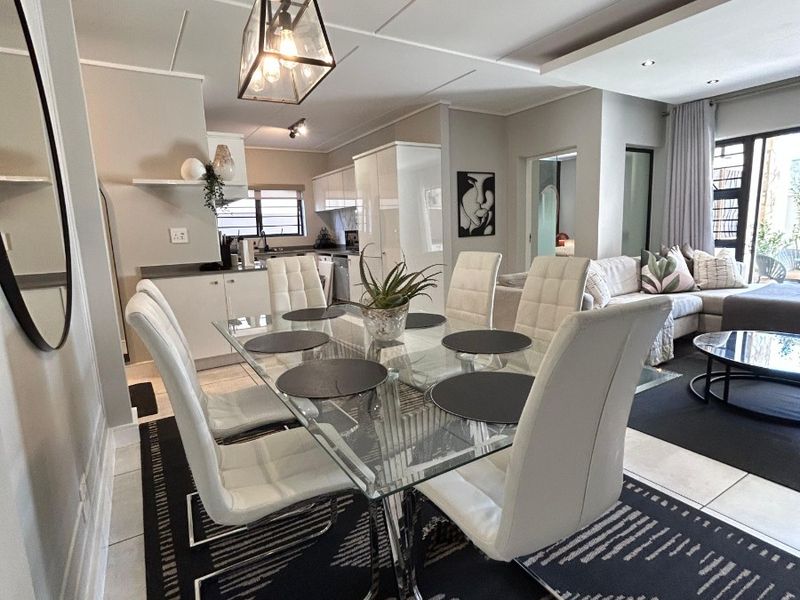 Modern open-plan living and dining area featuring tiled floors, contemporary pendant lighting, and seamless flow into a well-appointed kitchen with built-in cabinetry.