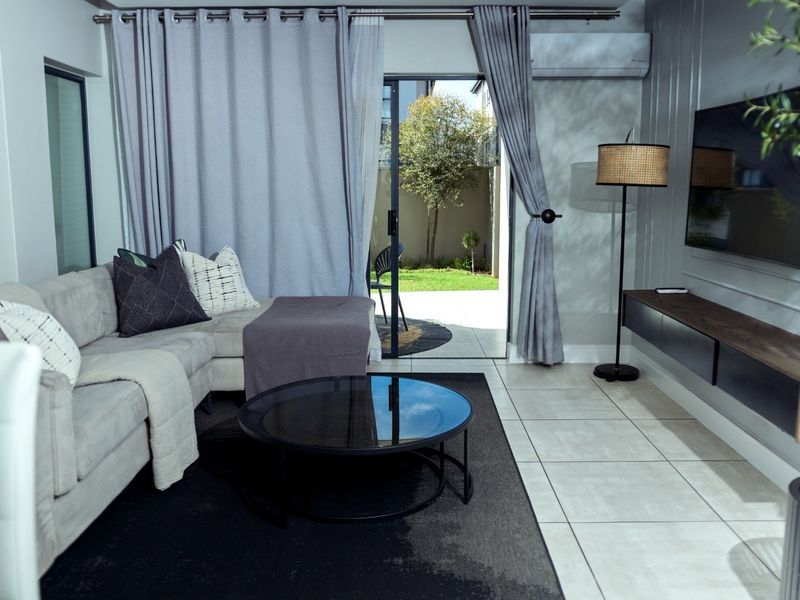 Modern living room featuring tiled floors, wainscoting, a floating media console, and direct access to a private patio through a sliding glass door.