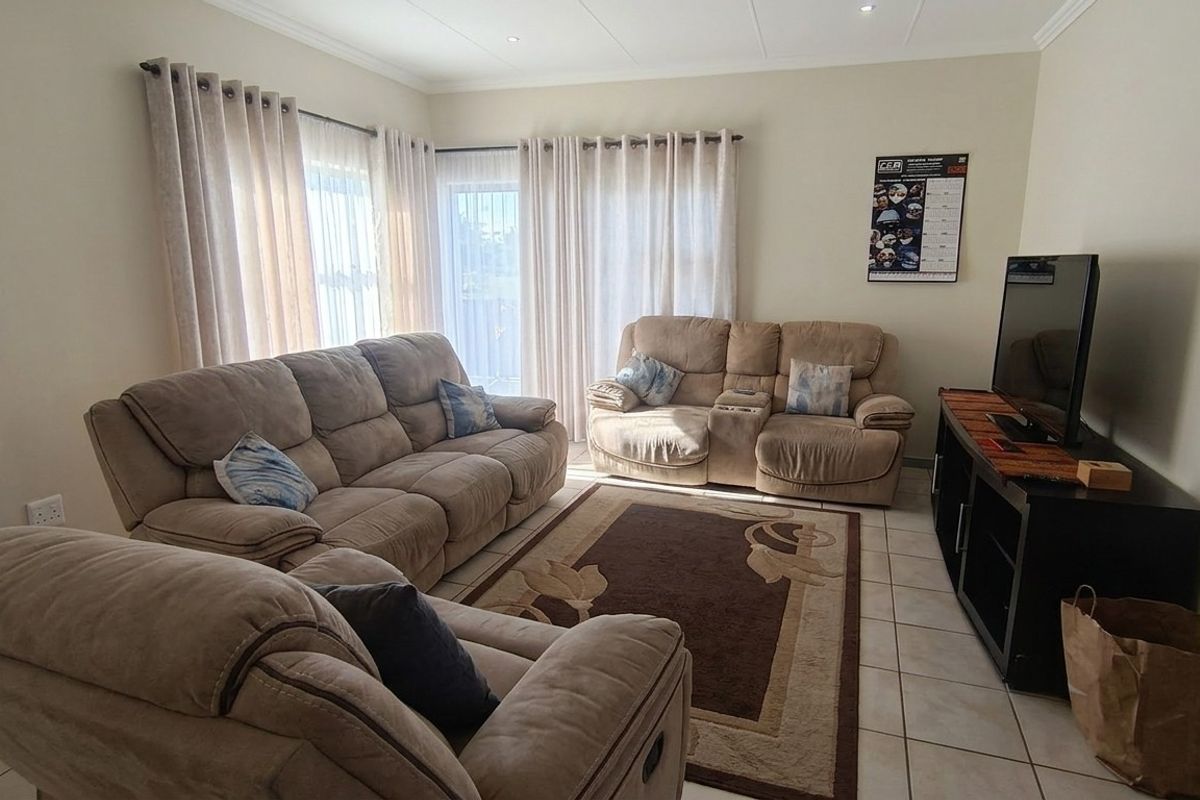 A comfortable living room featuring tiled flooring, recessed lighting, and large sliding glass doors that provide ample natural light.
