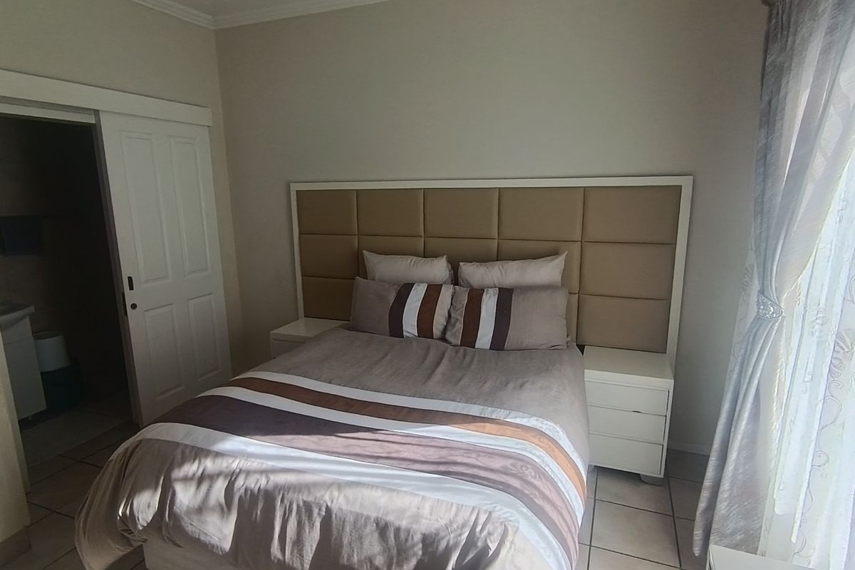 A well-maintained bedroom featuring tiled flooring, a neutral color palette, and direct access to an en-suite bathroom through a sliding door.