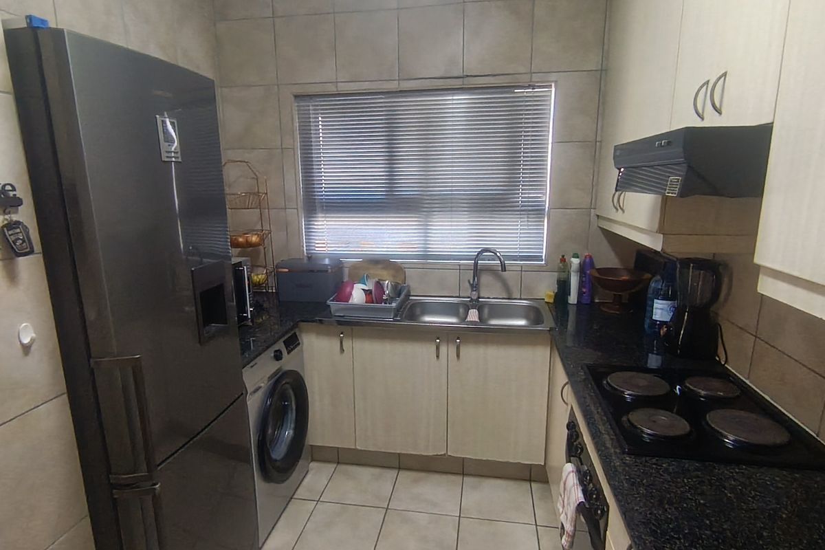 Compact kitchen featuring granite countertops, built-in cabinetry, electric hob with extractor fan, and tiled finishes throughout.