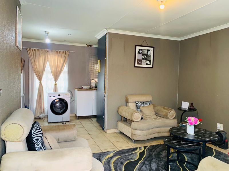 Open plan living area featuring tiled flooring and a small integrated sink unit, requiring minor finishing work to wall edges and ceiling fixtures.