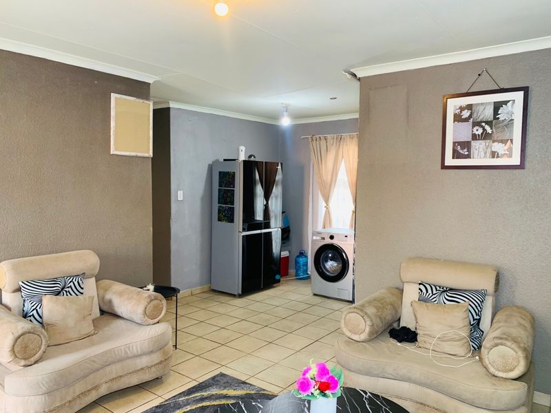 Open plan living area featuring tiled flooring and coved ceilings, providing a functional space with potential for cosmetic updates.