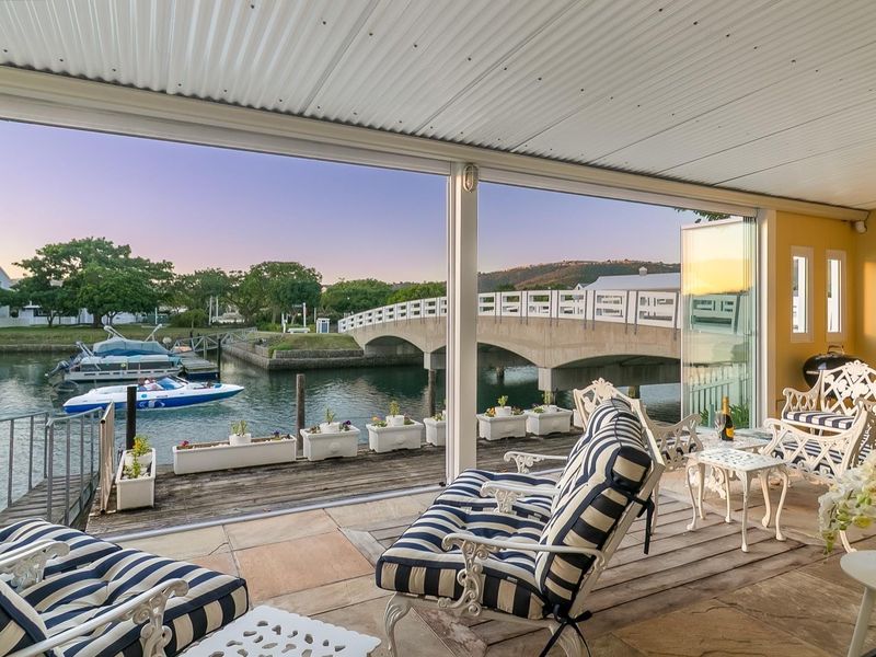 Covered patio featuring stone flooring and folding glass doors, offering direct views over the canal and bridge.
