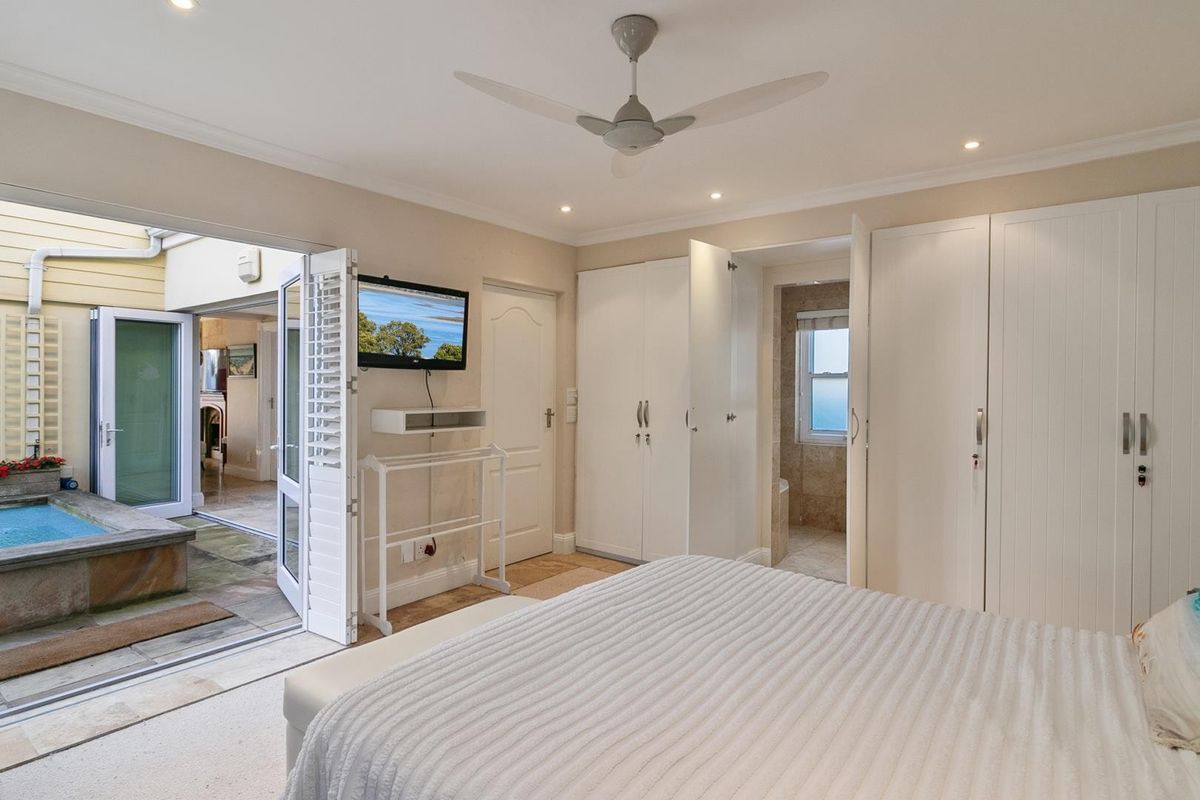 Spacious bedroom featuring built-in wardrobes, recessed lighting, a ceiling fan, and direct access to a private patio area with a plunge pool.