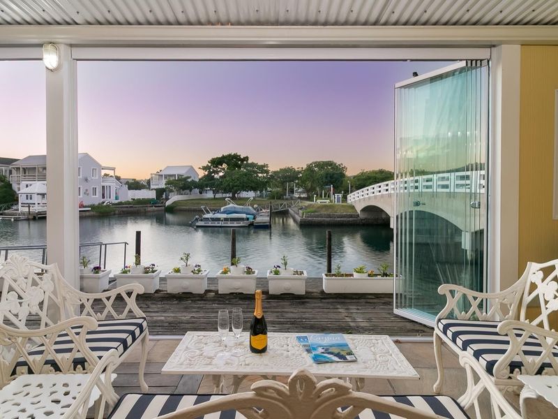 Covered patio featuring timber decking and stacking glass doors, offering direct access and scenic views of the canal and bridge.