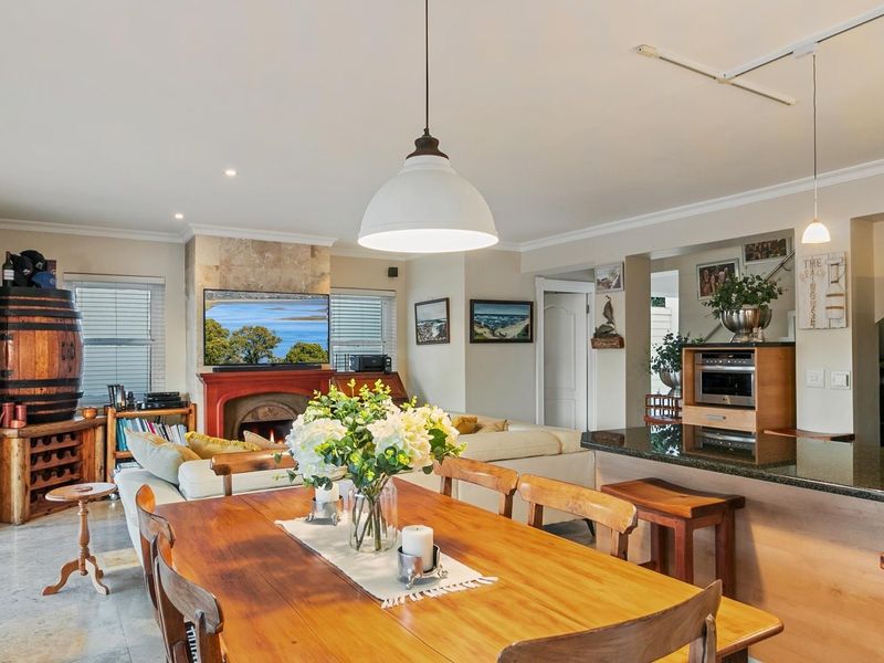 Open-plan living and dining area featuring a stone-surround fireplace, granite kitchen countertops, and integrated oven, creating a cohesive and functional living space.