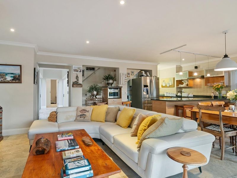 Spacious open-plan living, dining, and kitchen area featuring stone tile flooring, recessed lighting, and a functional kitchen layout with a central island.