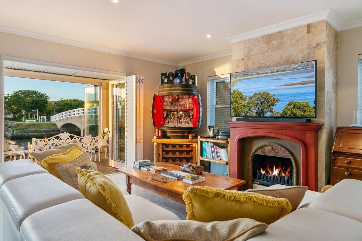 Cozy living room featuring a stone-clad fireplace, recessed lighting, and large stacking glass doors opening to a scenic outdoor patio area.