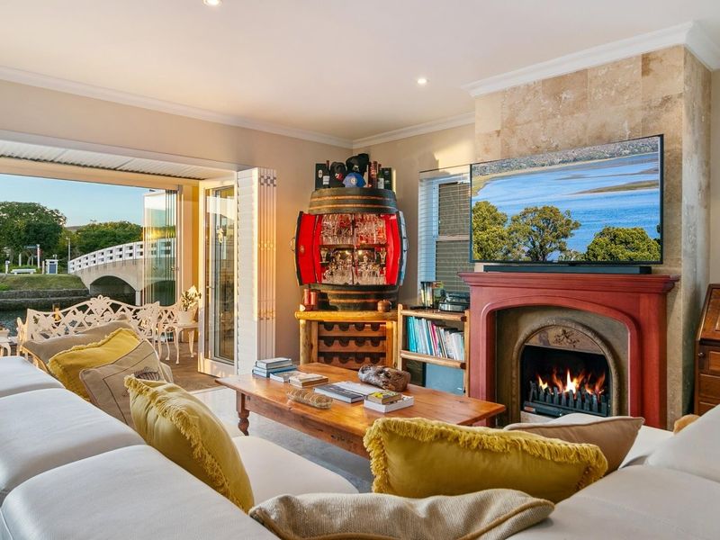 Cozy living room featuring a stone-clad fireplace, recessed lighting, and large stacking glass doors opening to a scenic outdoor patio area.