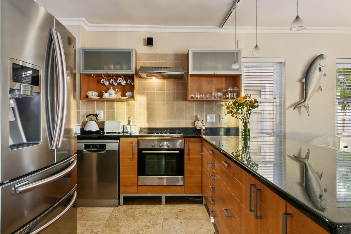 A well-maintained kitchen featuring wooden cabinetry, granite countertops, a built-in oven, electric hob, and a tiled backsplash.
