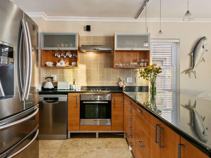 A well-maintained kitchen featuring wooden cabinetry, granite countertops, a built-in oven, electric hob, and a tiled backsplash.
