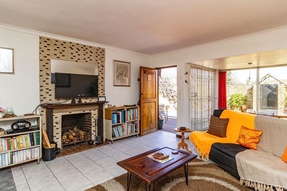 Spacious living room featuring a tiled floor, a central fireplace with a decorative surround, and direct access to an outdoor patio area.