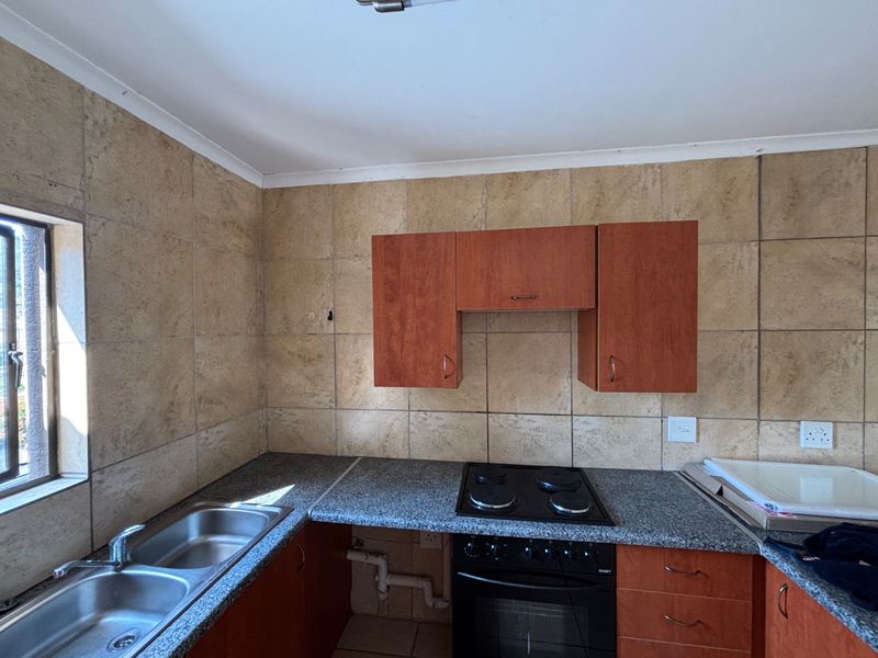 A functional kitchen featuring granite countertops, a double bowl sink, built-in oven, electric hob, and tiled backsplash with ample cabinetry.