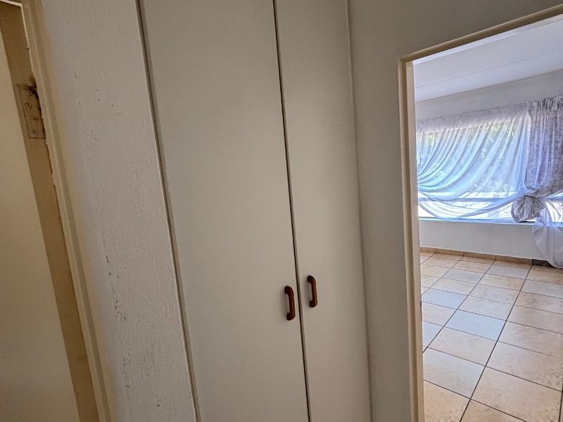 A functional hallway featuring a built-in storage cupboard and tiled flooring, providing access to adjacent living areas.