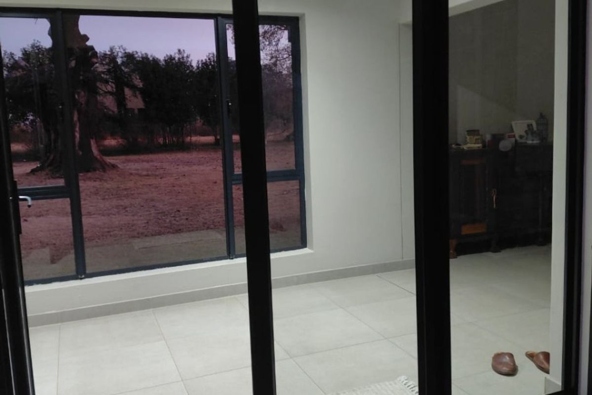 Bright and spacious living area featuring large format floor tiles and modern black aluminium sliding doors with views of the surrounding farm landscape.