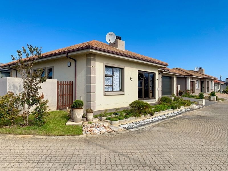 Front elevation of a well-maintained single-story residential house featuring a tiled roof, paved driveway, and integrated garage.