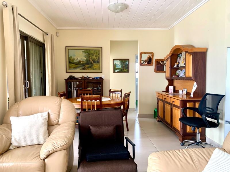 A living room featuring tiled flooring, a tongue and groove ceiling, and a sliding glass door providing access to the exterior.
