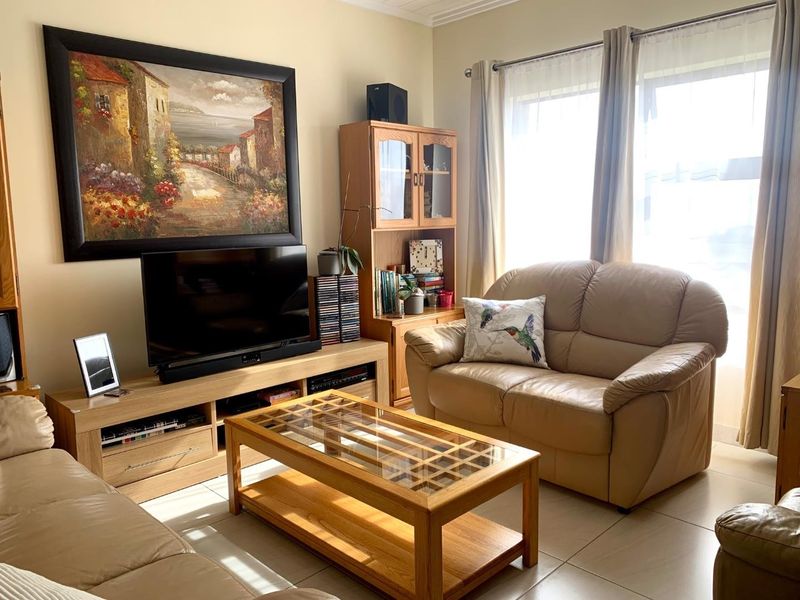 A bright living room featuring neutral tiled flooring and large windows that allow for ample natural light.