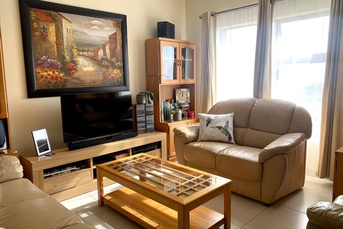A bright living room featuring neutral tiled flooring and large windows that allow for ample natural light.