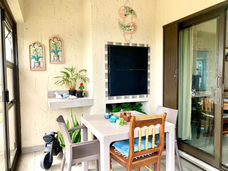 A covered patio area featuring a built-in braai, tiled flooring, and sliding glass door access to the interior living space.