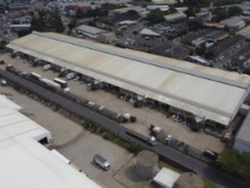 Aerial view of a large industrial warehouse facility featuring extensive metal roofing and a dedicated loading yard area.