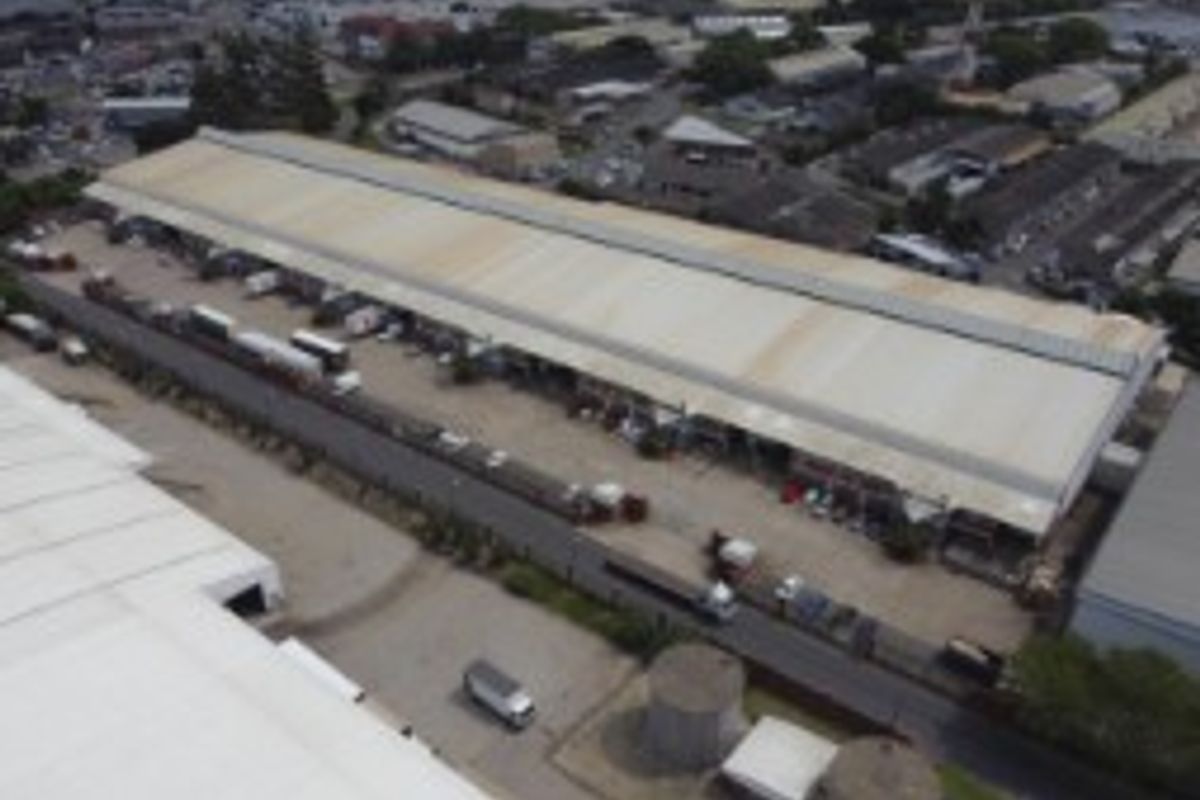 Aerial view of a large industrial warehouse facility featuring extensive metal roofing and a dedicated loading yard area.