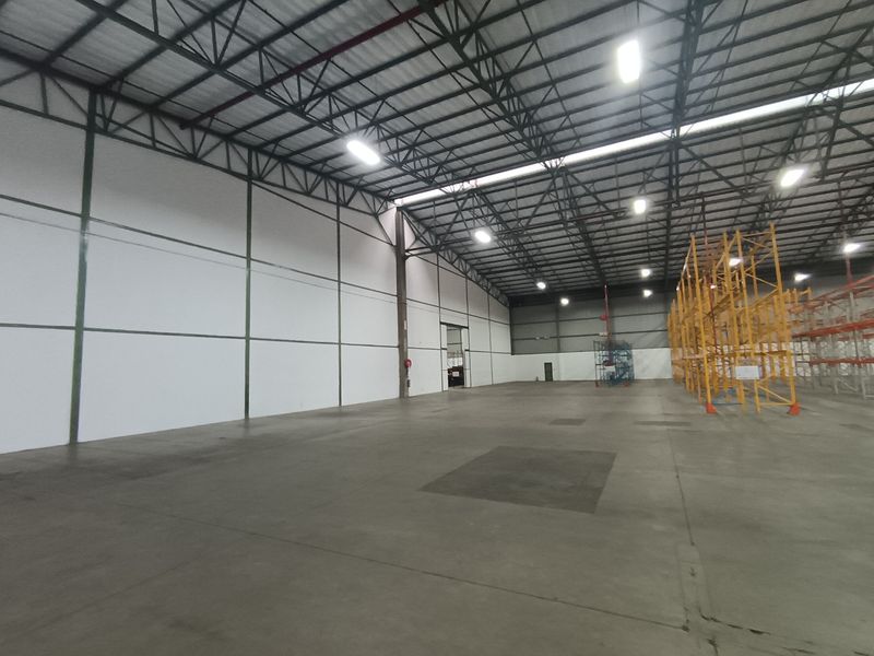 Spacious industrial warehouse featuring high ceilings with exposed steel trusses, concrete flooring, and integrated pallet racking systems, suitable for storage or manufacturing operations.