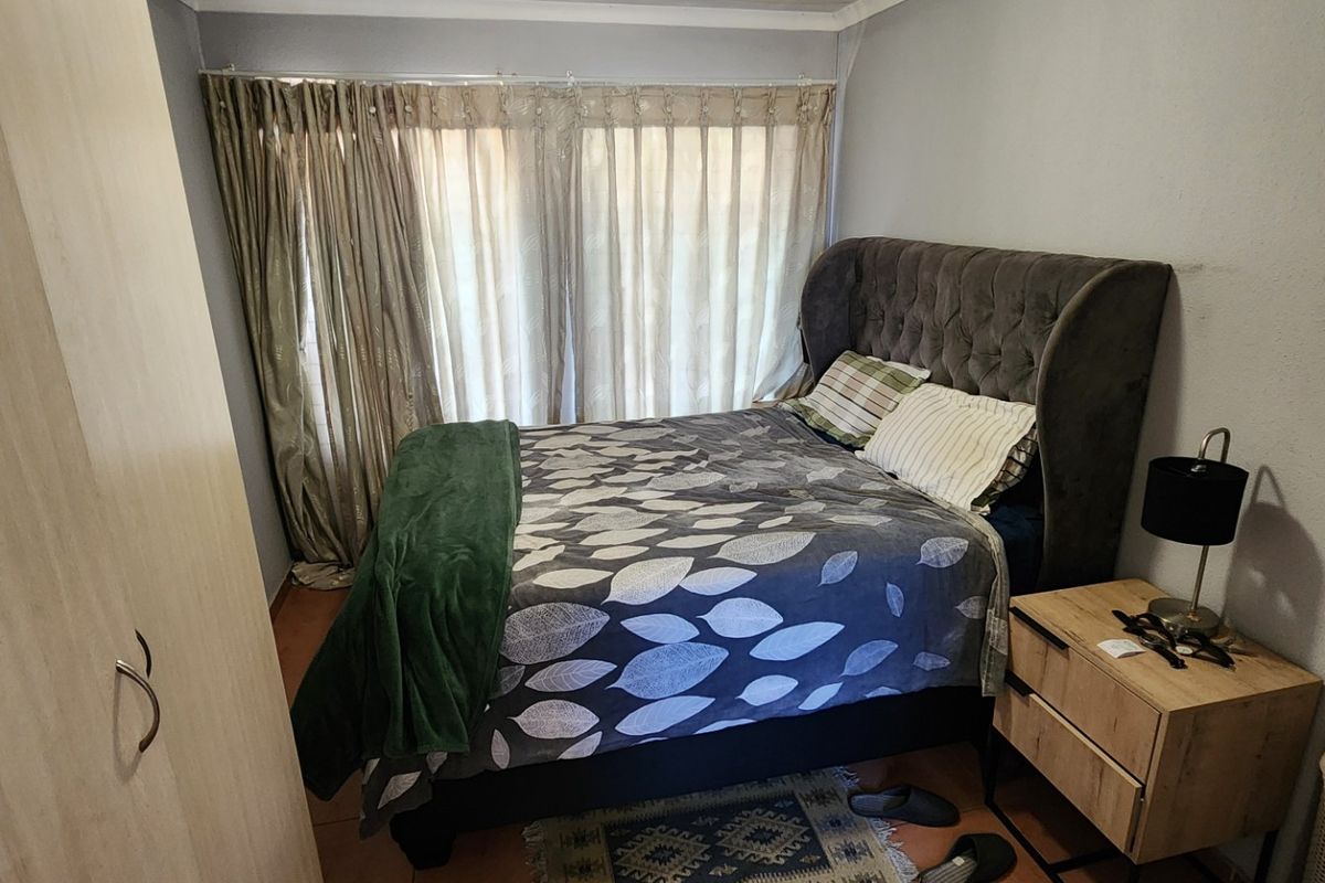 A functional bedroom featuring a built-in wardrobe and large window with curtain tracks, providing a comfortable and practical living space.