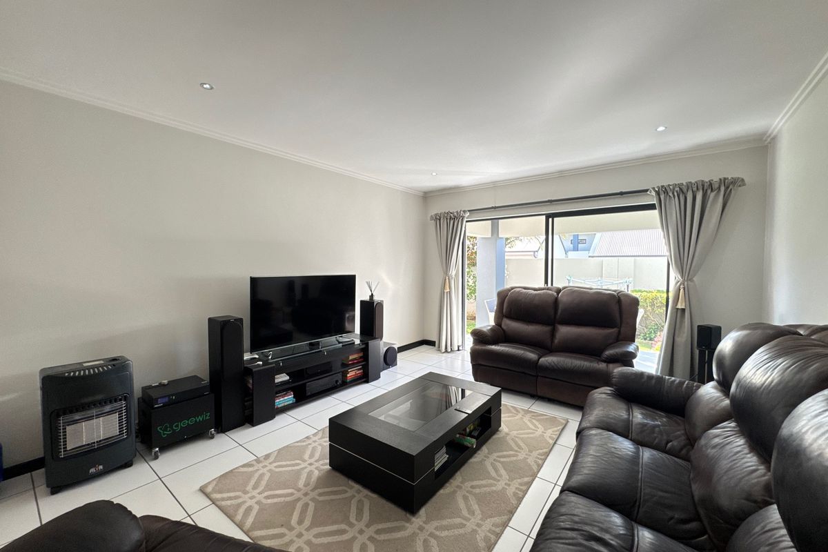 A bright living room featuring tiled flooring, recessed downlights, and a large sliding glass door providing access to the outdoor area.