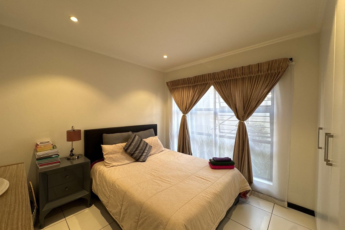A well-maintained bedroom featuring tiled flooring, recessed downlighting, and a built-in wardrobe, offering a clean and functional living space.