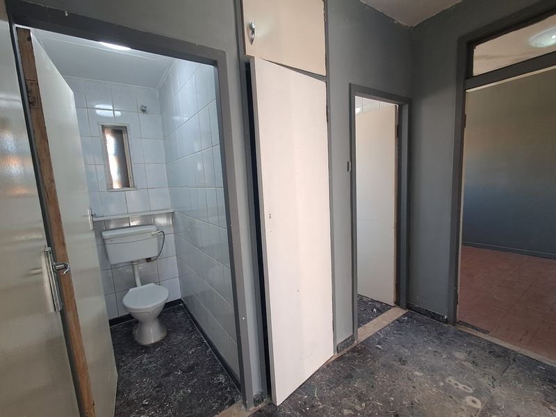 A functional hallway area featuring access to a tiled bathroom and adjacent rooms, with built-in storage and neutral grey wall finishes.
