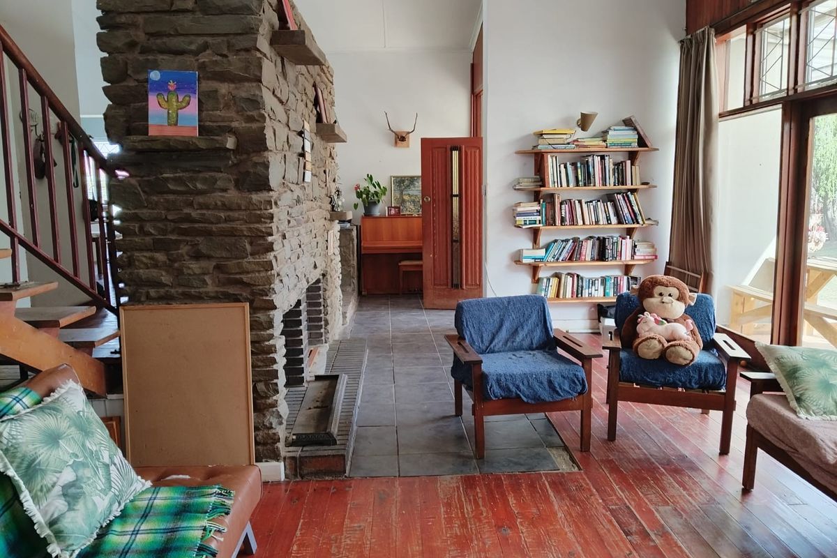Spacious living room featuring a prominent stone fireplace, timber flooring, and large windows that provide ample natural light.