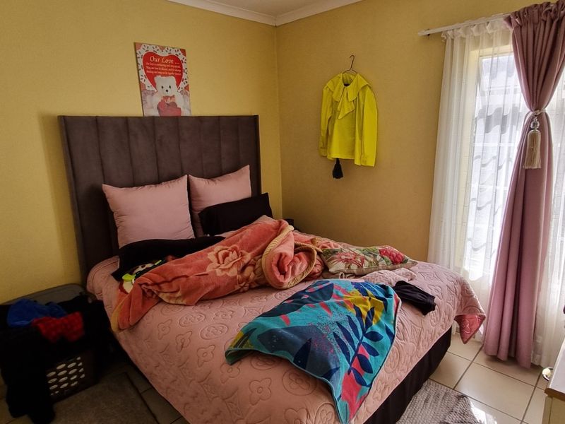 A standard bedroom featuring tiled flooring and natural light through a window with installed curtain rails.