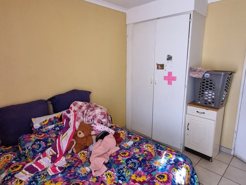 A bedroom featuring tiled flooring and a built-in wardrobe, providing functional storage space.