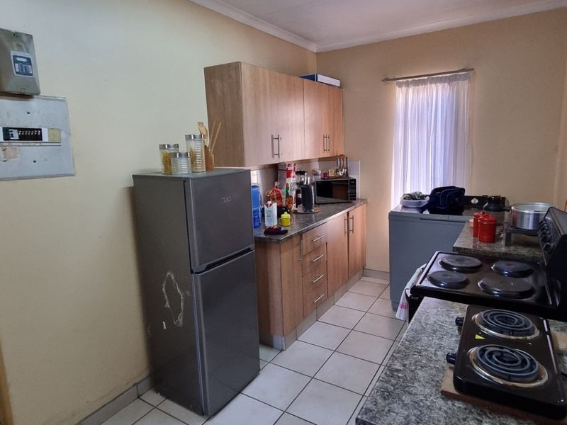 A functional kitchen featuring laminate cabinetry, granite countertops, and tiled flooring, offering a practical layout with potential for cosmetic updates.